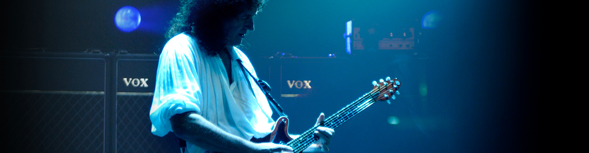 Brian May playing electric guitar in concert