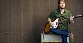 artist, Chris Shiflett, sitting on VOX amplifier and playing electric guitar