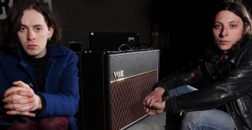 two musicians sitting on either side of VOX amplifier