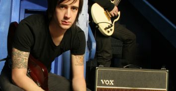 artist, Nick Wheeler, holding electric guitar next to VOX amplifier