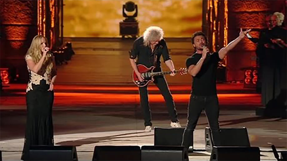 Brian May in concertbehind two singers