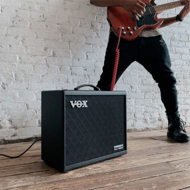 Vox Cambridge50 guitar modeling amp sitting on the floor in front of a man playing an electric guitar