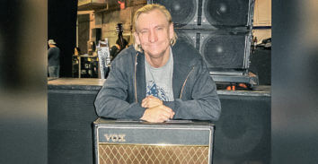 man leaning on VOX amplifier in front of stage