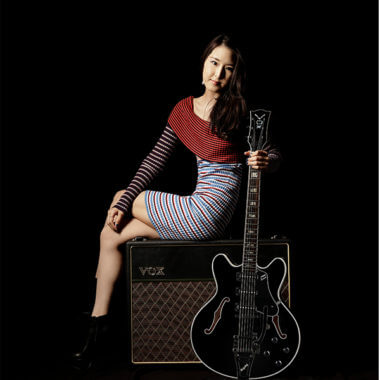 woman sitting on amp and holding electric guitar
