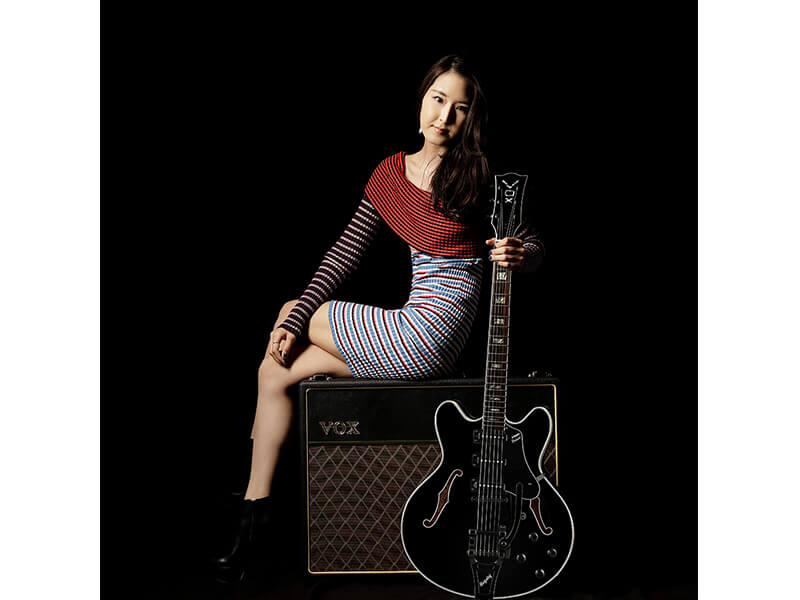 woman sitting on amp and holding electric guitar