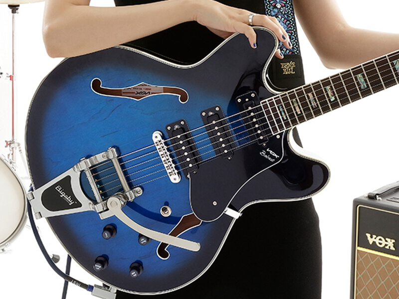 partial view of musician holding black and blue electric guitar