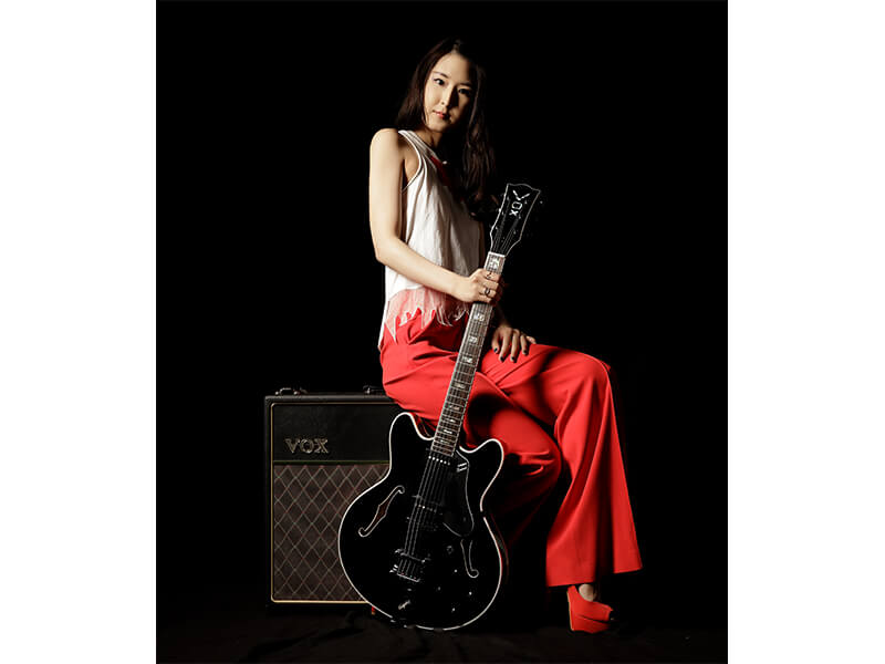 woman sitting on amplifier holding electric guitar