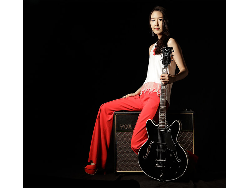 woman sitting on amplifier holding electric guitar