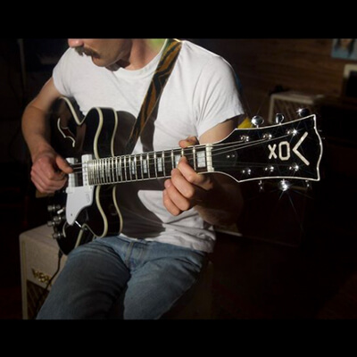 partial view of man playing black VOX electric guitar
