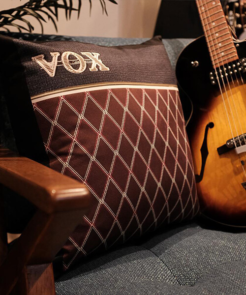 Vox throw pillow on a chair next to a guitar