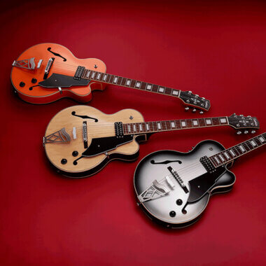 Three different colors of Vox Giulietta Vga-5td Archtop Electric Guitar on red carpet.