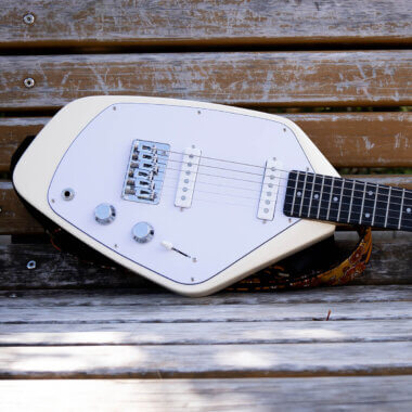 Vox Mark V Mini Guitar white body close up on wooden bench.