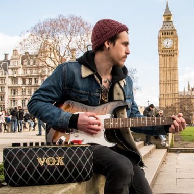 man playing electric guitar and using VOX AudioAir GT beside Big Ben in London