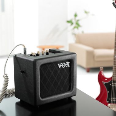 VOX mini amplifier beside red electric guitar