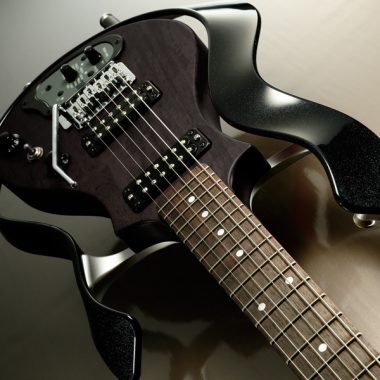closeup of body of black VOX electric guitar